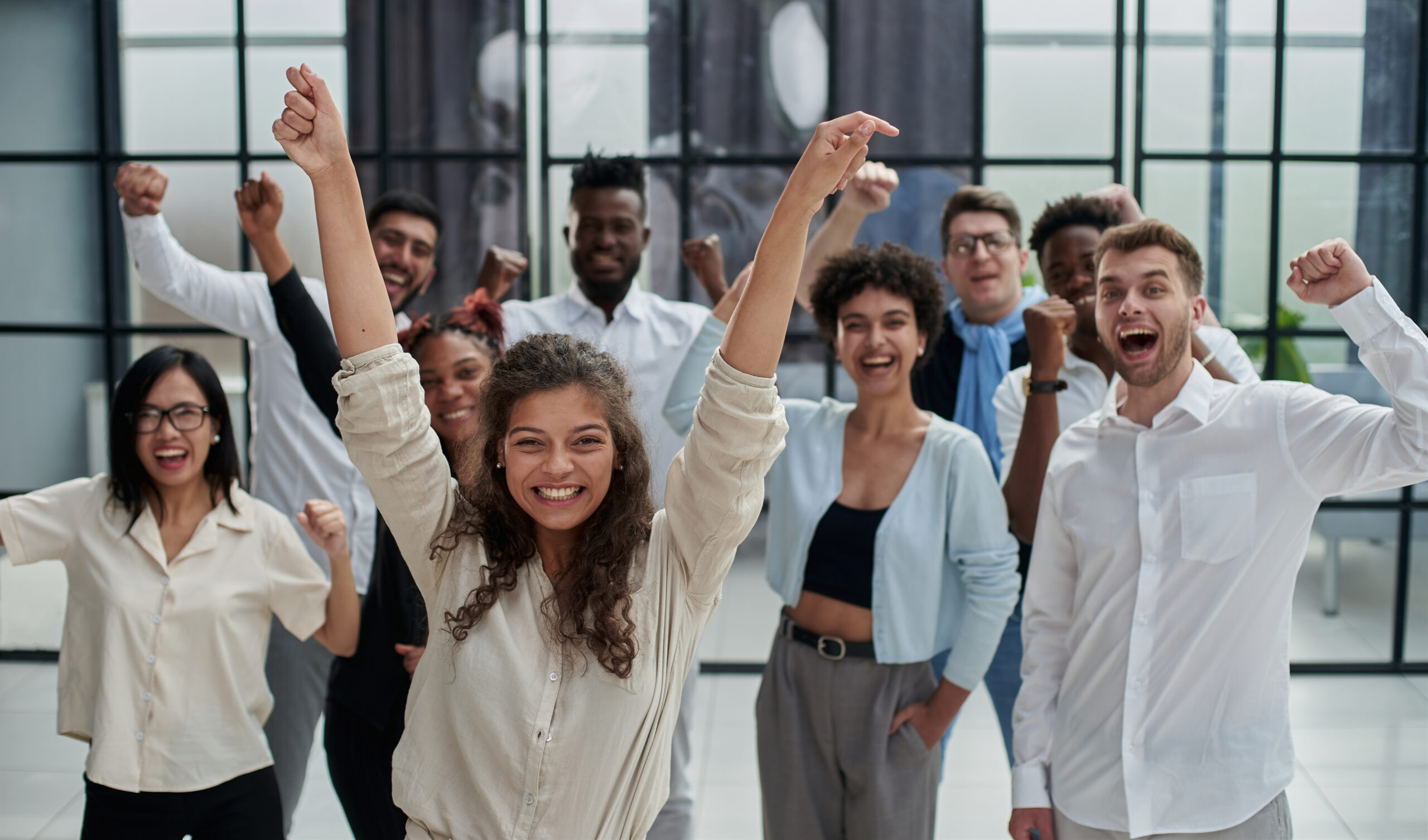 un groupe d'étudiants sourit et lèvent les bras